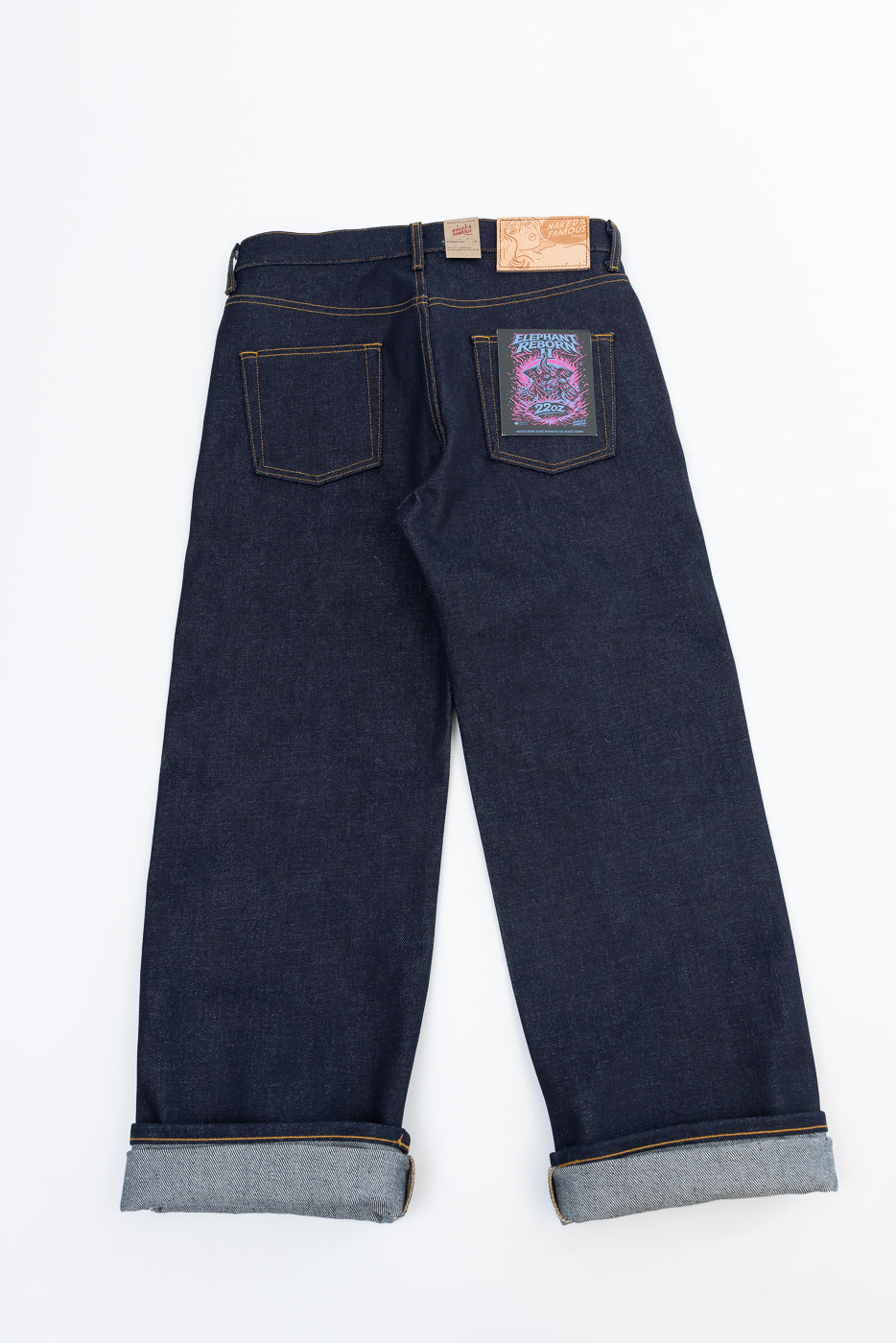 Back view flat lay of dark indigo selvedge denim jeans with cuffed hems.