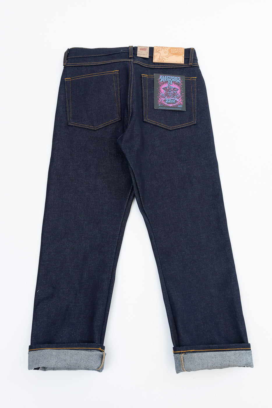 Back view flat lay of dark indigo selvedge denim jeans with leather patch and graphic pocket.