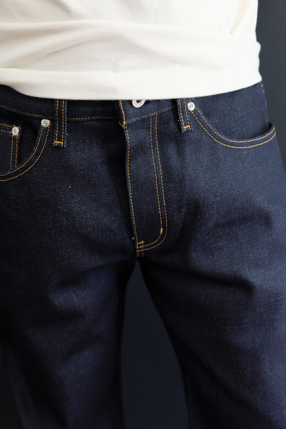 Close-up front view of dark indigo selvedge denim jeans on a male model, 5'9