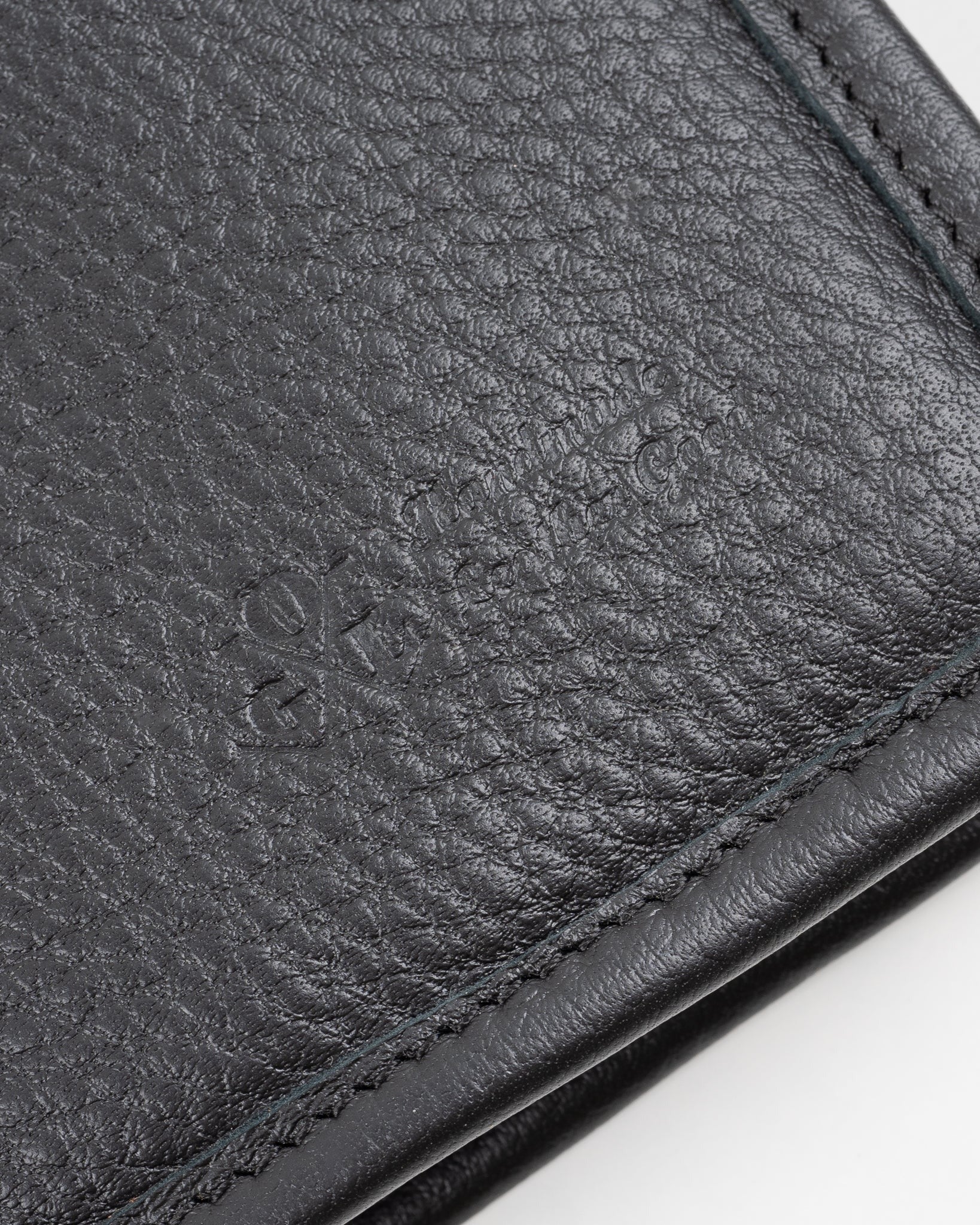 Close-up of black pebbled leather accessory front, showing textured grain and stitching detail.