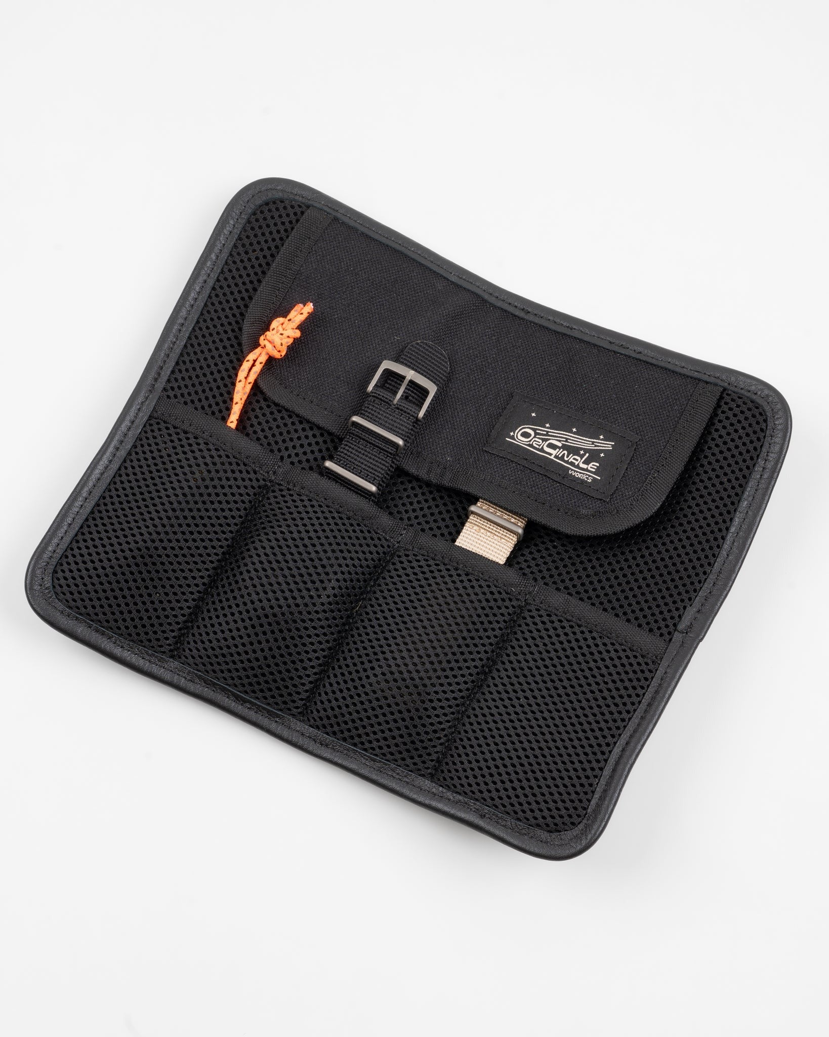 Flat lay of black watch pouch front, showing mesh fabric, buckle, orange cord, and logo tag.