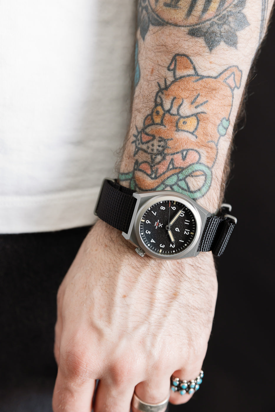 Close-up of black dial field watch on a male model’s left wrist, 5'9