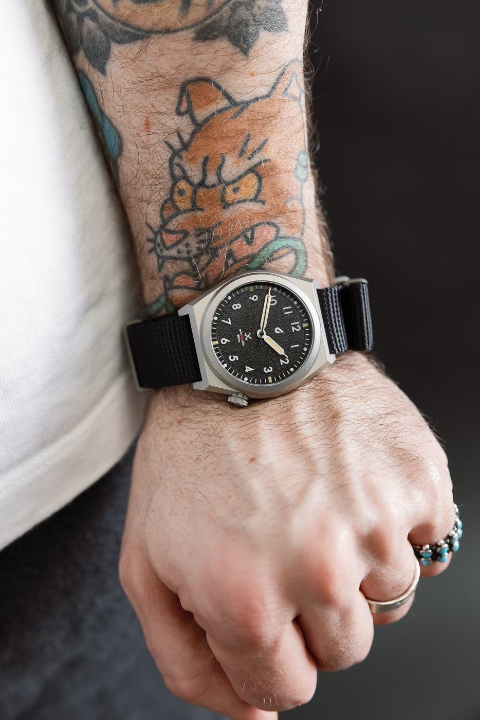 Close-up of black field watch on male model’s wrist, left side view, 5'9