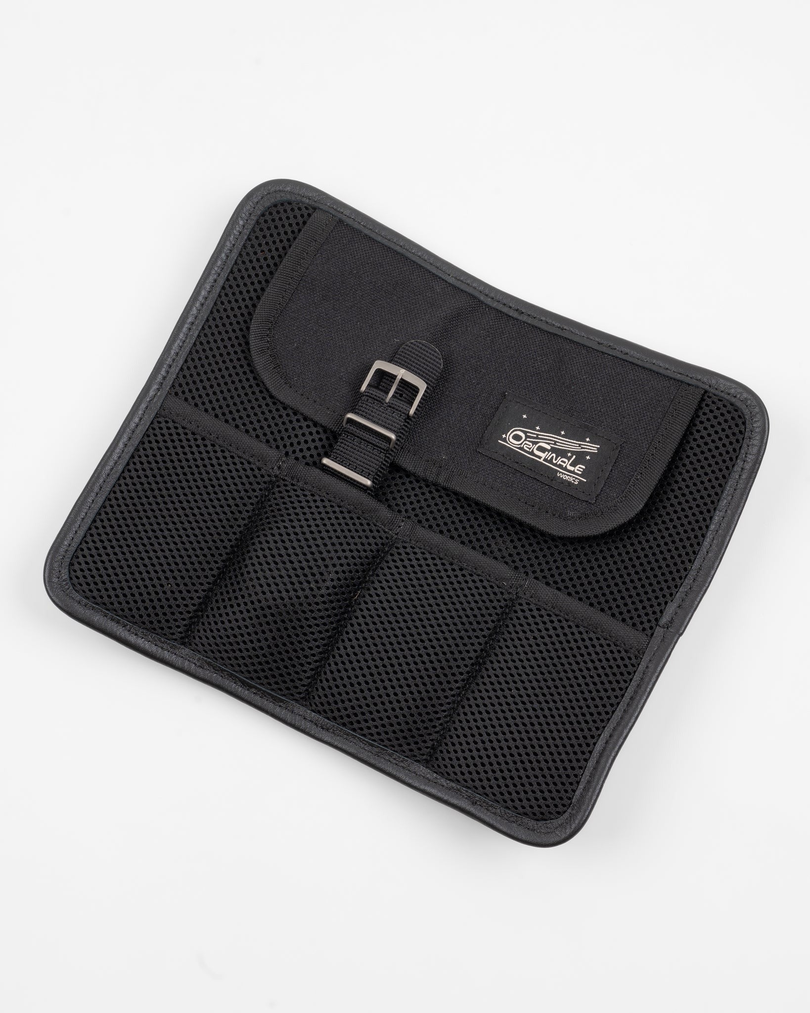 Flat lay of a black nylon watch roll, front side, showing mesh pockets and buckle closure detail.