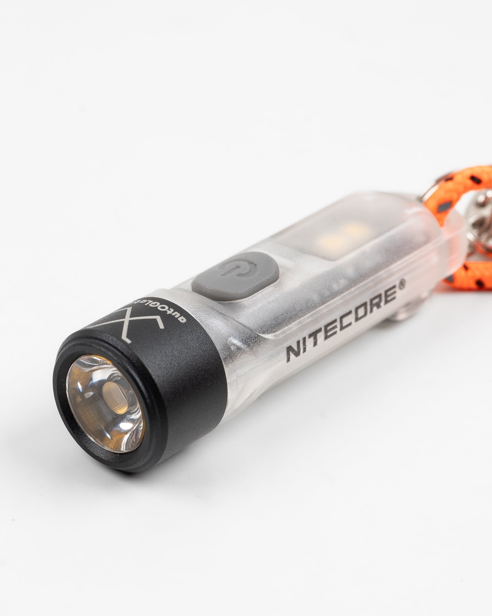 Close-up of Nitecore compact keychain flashlight, front lens and power button in focus.