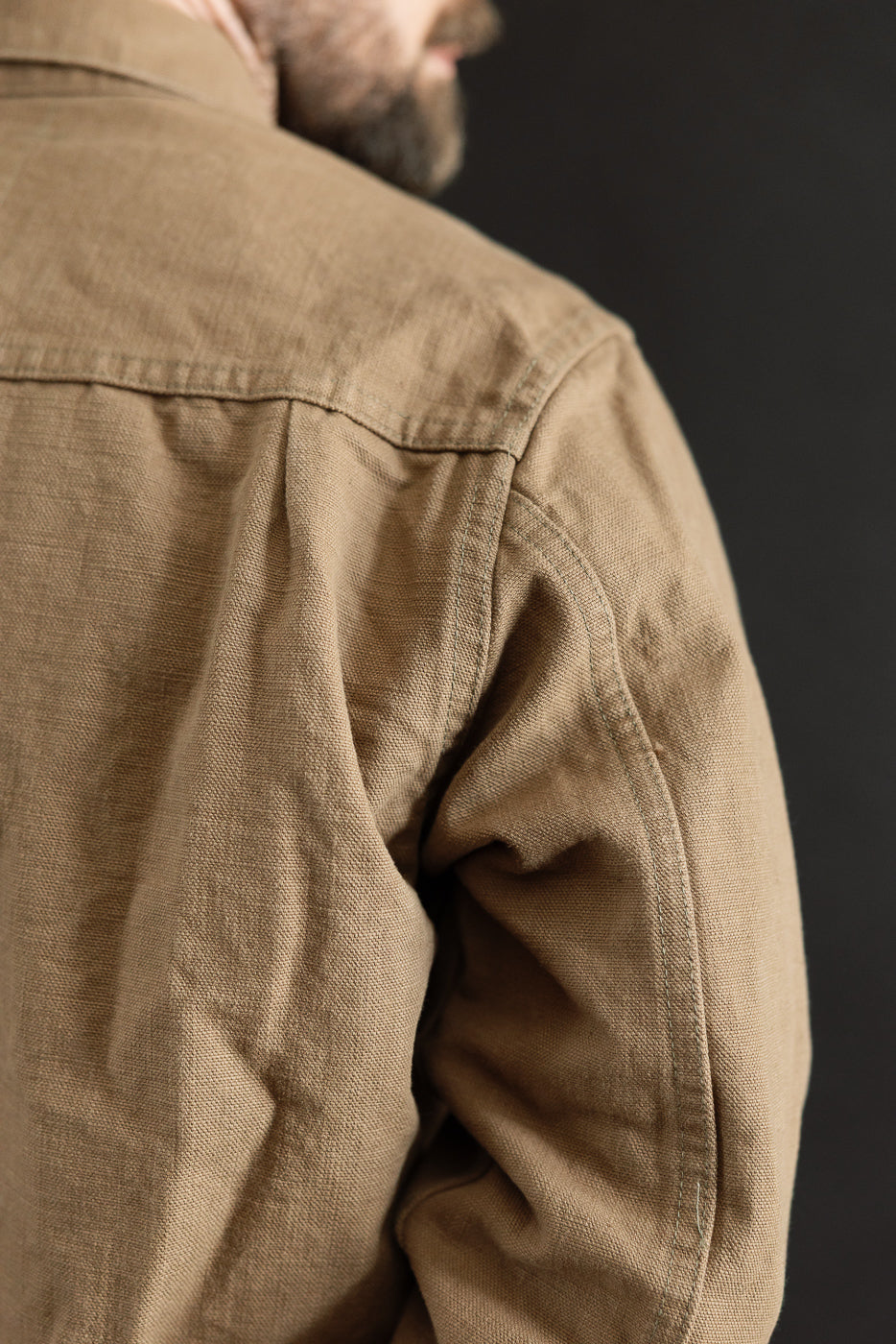 Close-up of the 01507-HOX-BRK jacket showcasing its light brown canvas texture, shoulder seam lines, and fabric bunching at the elbow, highlighting the intricate weave of this heritage-inspired workwear piece.
