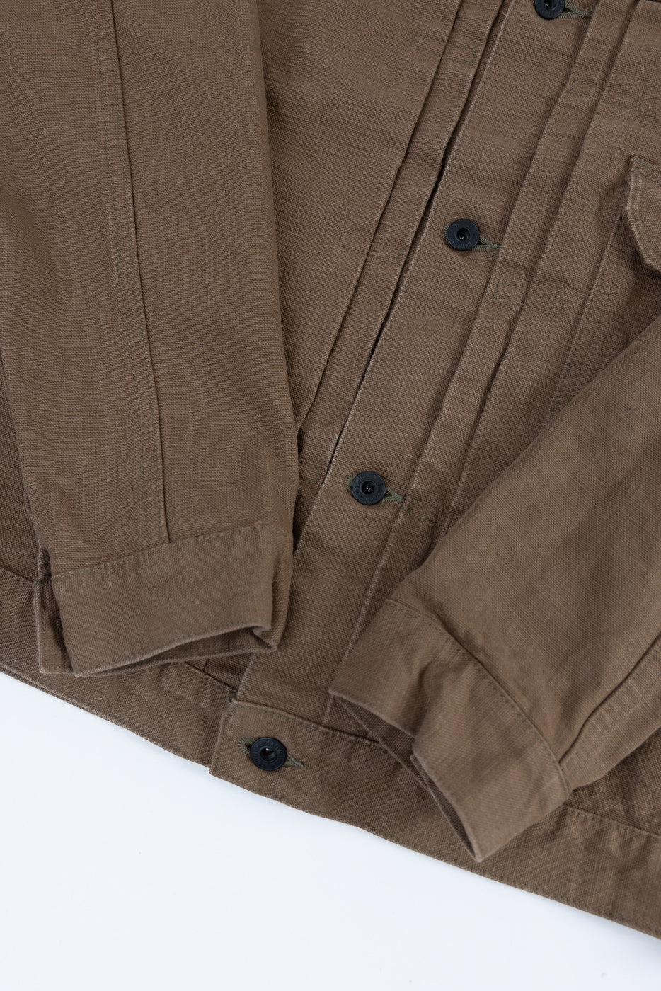 Close-up of the 01507-HOX-BRK - 13oz Brown Khaki Sulfur Dyed Heavy Oxford Jacket - Type I, featuring black buttons, pleated front, a single chest pocket, and a cinch back, showcasing its workwear-inspired design.