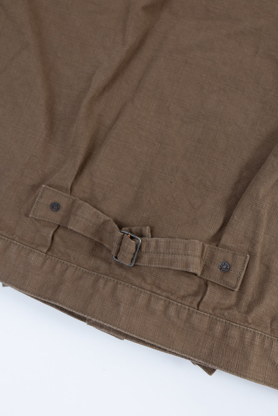 Close-up of the 01507-HOX-BRK - 13oz Brown Khaki Sulfur Dyed Heavy Oxford Jacket - Type I, focusing on the adjustable fabric tab with metal buckle and snap-button tabs at the hem.