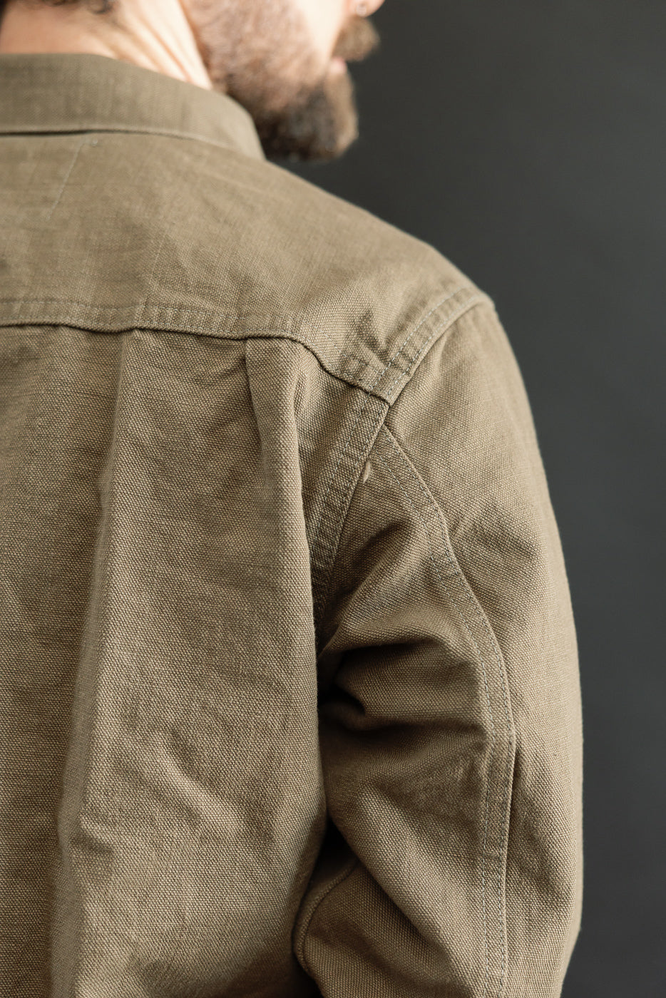 Close-up of 01507-HOX-OLB - 13oz Olive Khaki Sulfur Dyed Heavy Oxford Jacket - Type I, showcasing its textured canvas-style fabric and classic workwear silhouette with visible pleats and stitching.
