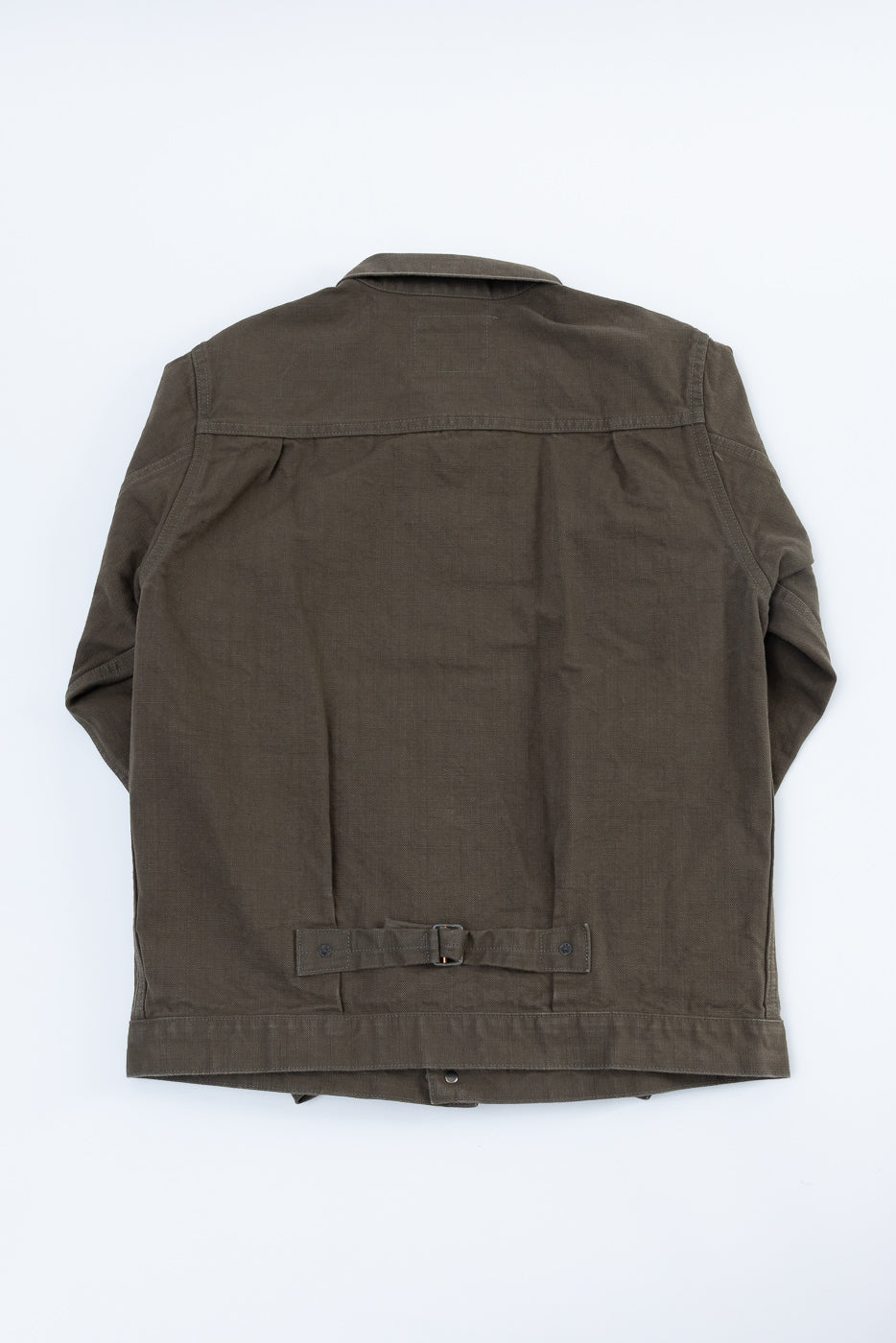 The 01507-HOX-OLB jacket features an olive-khaki hue with a cinch-strap, showcasing its workwear-inspired design. Its sulfur-dyed oxford fabric offers texture characteristic of ONI Denim's heritage style.