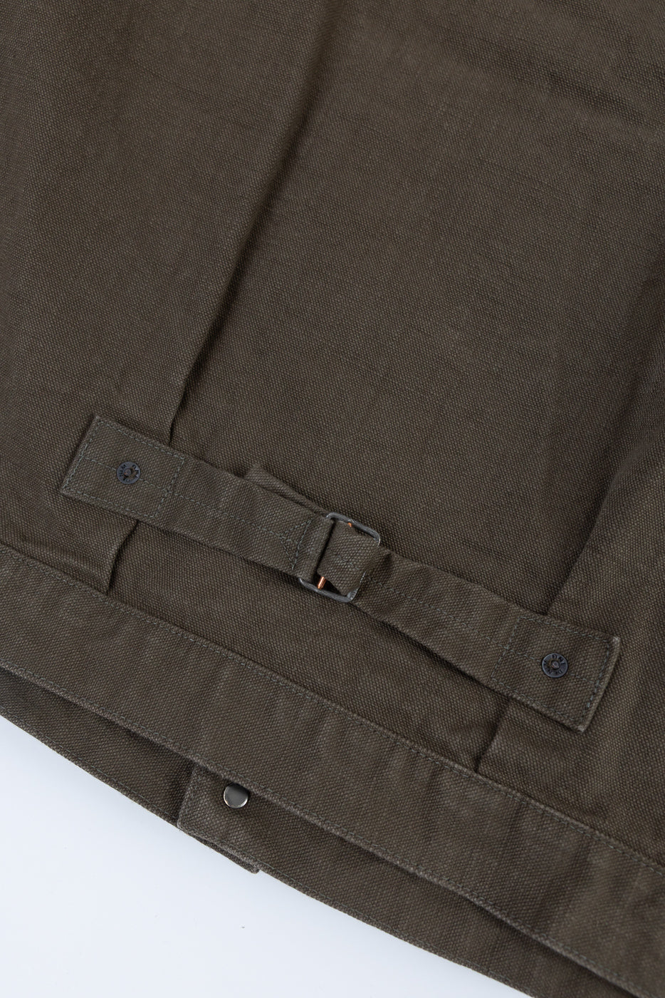 Close-up of the 01507-HOX-OLB - 13oz Olive Khaki Sulfur Dyed Heavy Oxford Jacket - Type I, showcasing the adjustable waist strap with a metal buckle and snap-button fasteners on the hem.