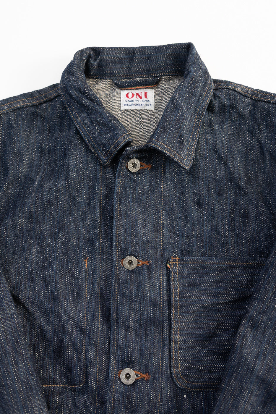 Close-up front view of ONI 16oz Kase denim selvedge jacket showing textured fabric, collar, buttons, and chest pocket, product flat lay for Dant contemporary casual apparel.