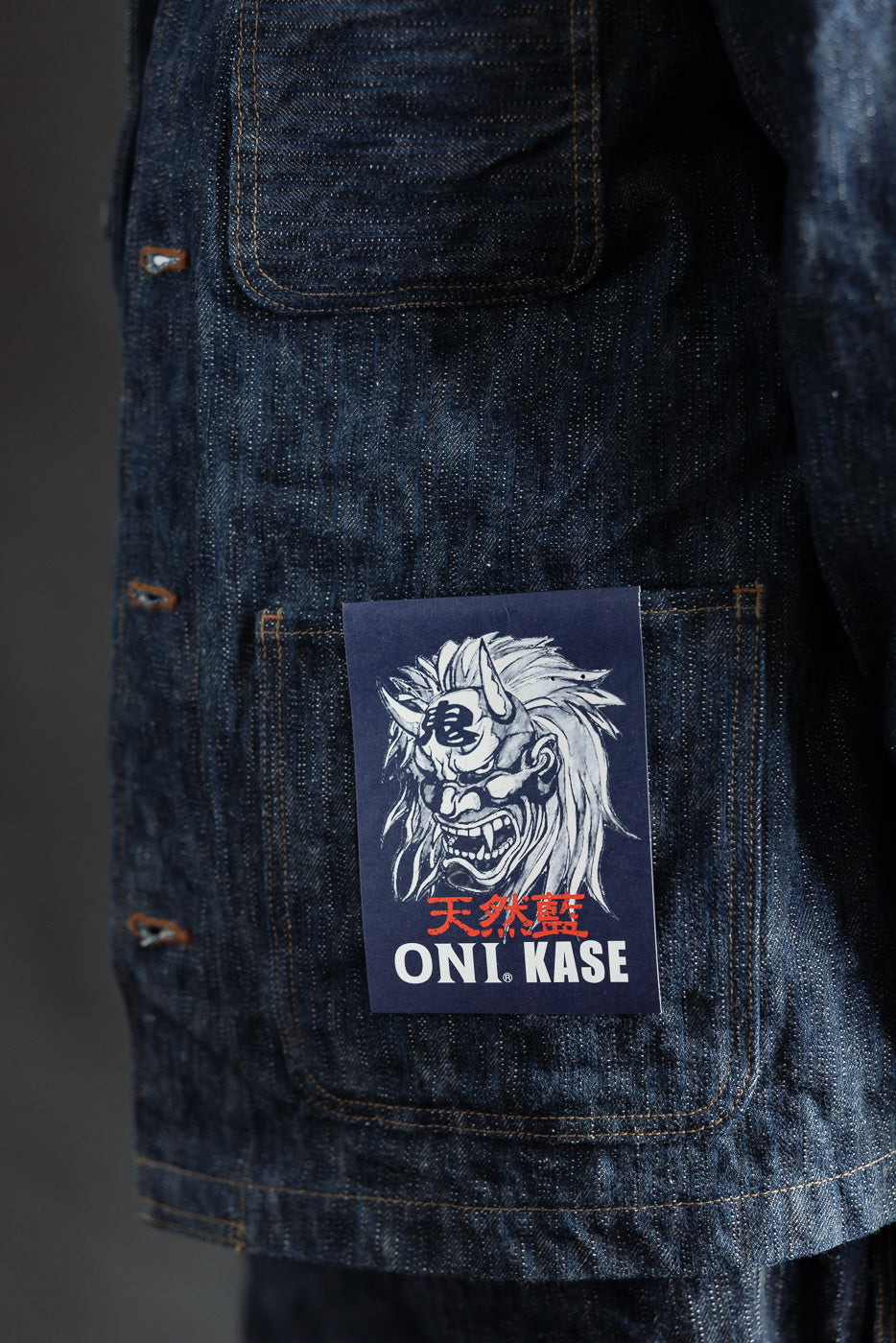 Close-up of ONI KASE selvedge denim jacket front pocket, visible patch, rugged texture