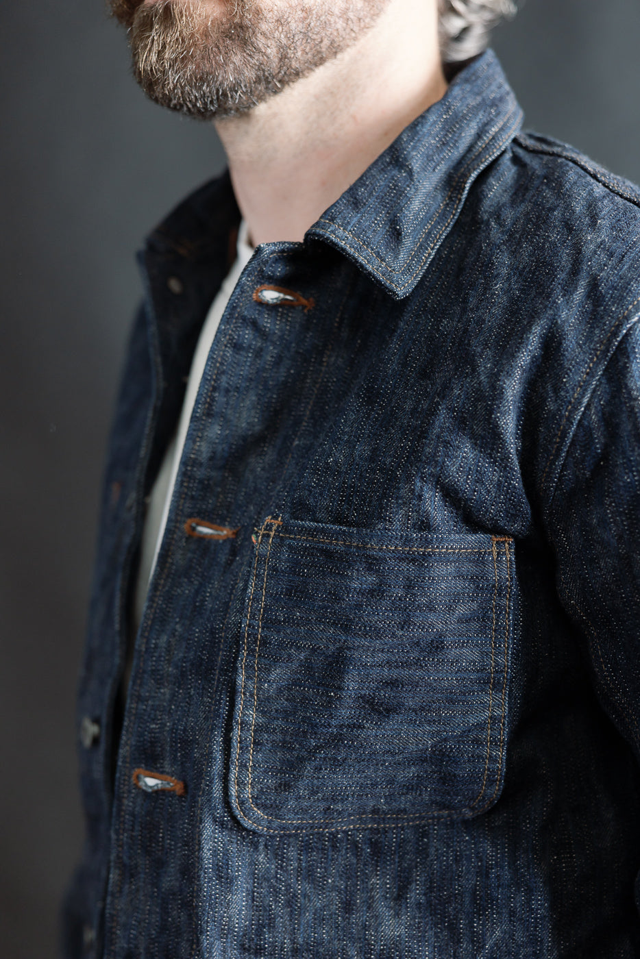 Close-up of front left side of selvedge denim chore jacket on male model, 5'9