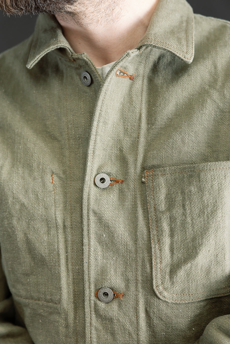 Close-up of front chest and collar of olive selvedge denim coverall jacket on male model 5'9