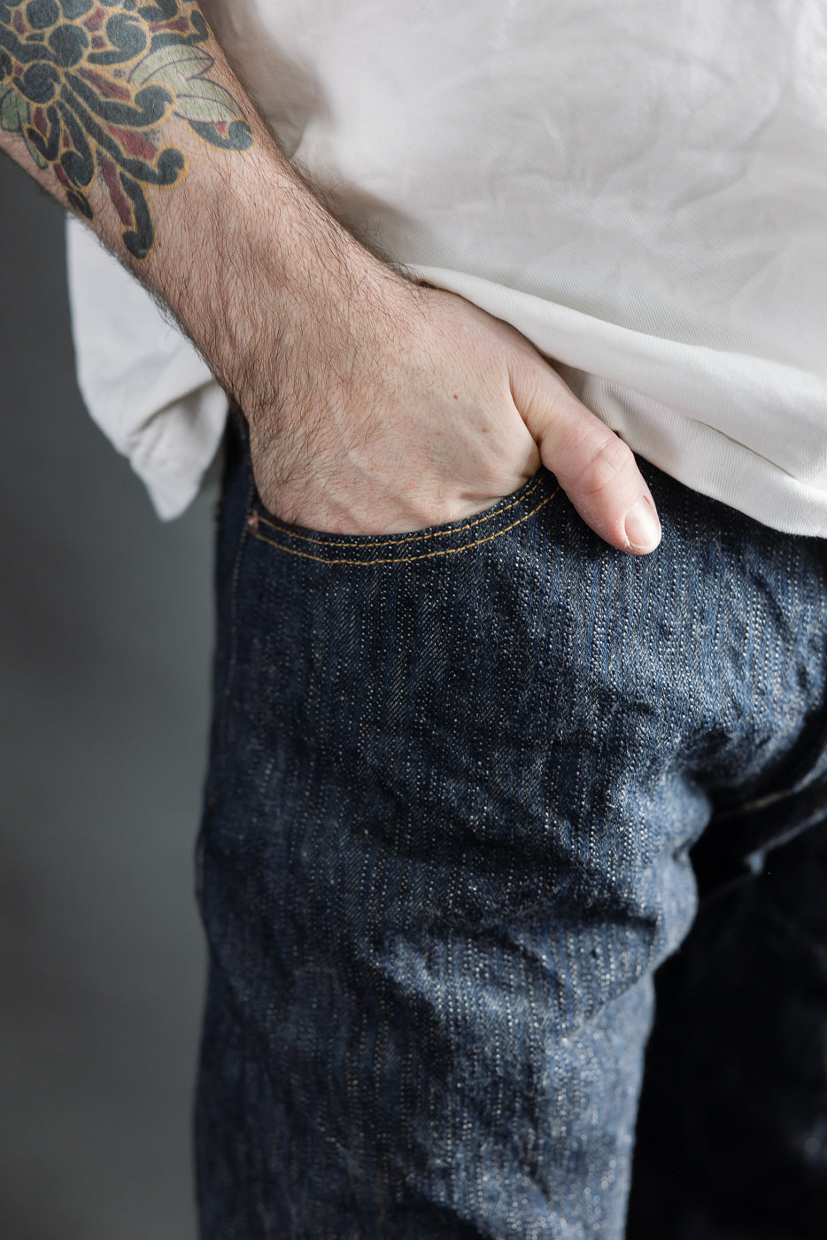 Close-up of front left pocket and upper thigh of selvedge denim jeans on male model, 5'9