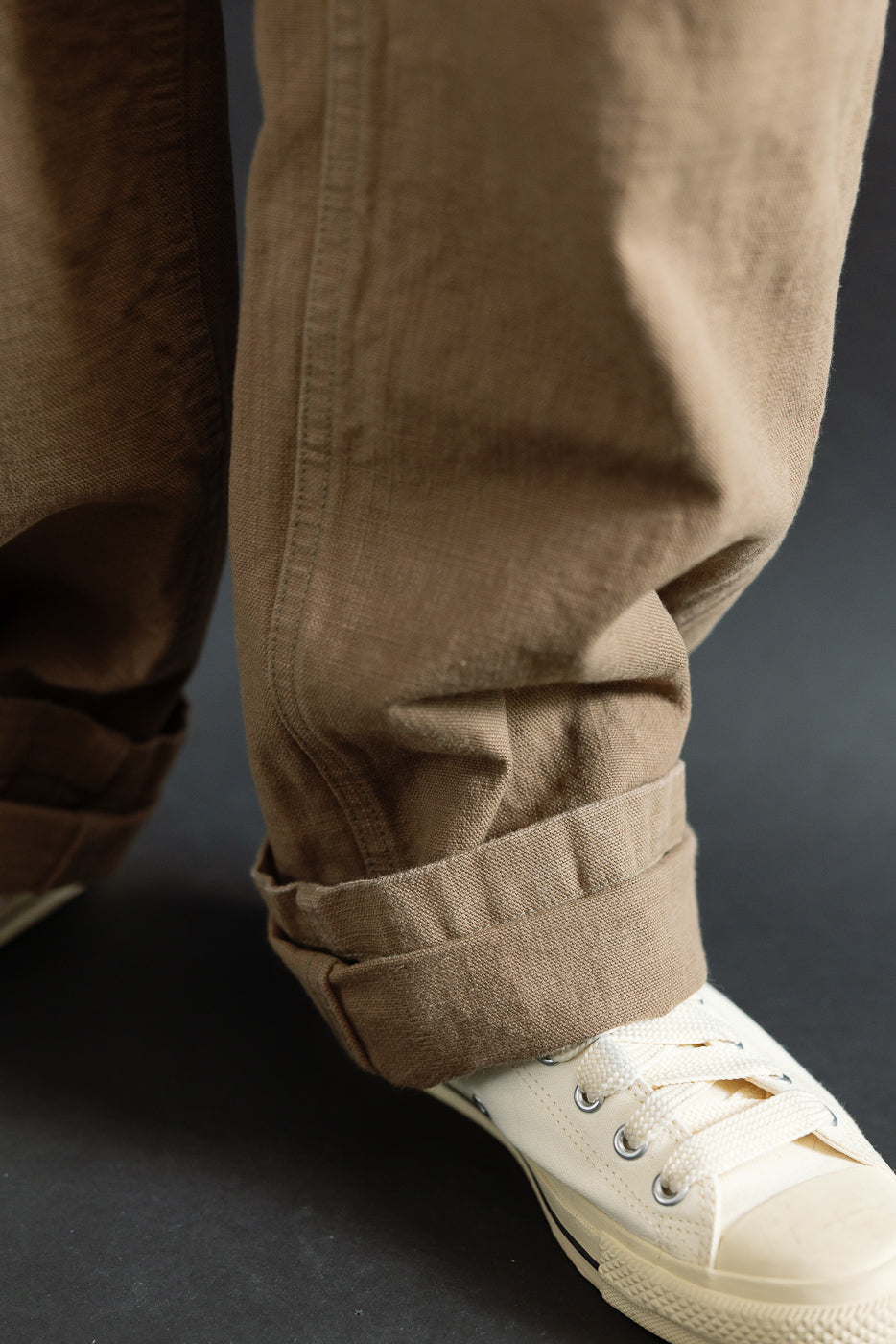 Close-up of the ONI Denim 207-HOX-BRK - 13oz Brown Khaki Sulfur Dyed Heavy Oxford Baker Pants, showcasing the textured fabric and cuffed hem over a white canvas sneaker.