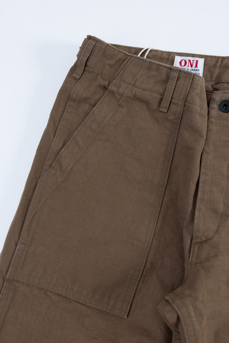 Close-up of the 207-HOX-BRK - 13oz Brown Khaki Sulfur Dyed Heavy Oxford Baker Pants, highlighting the angled patch pocket, belt loops, button closure, and ONI – Made in Japan label.
