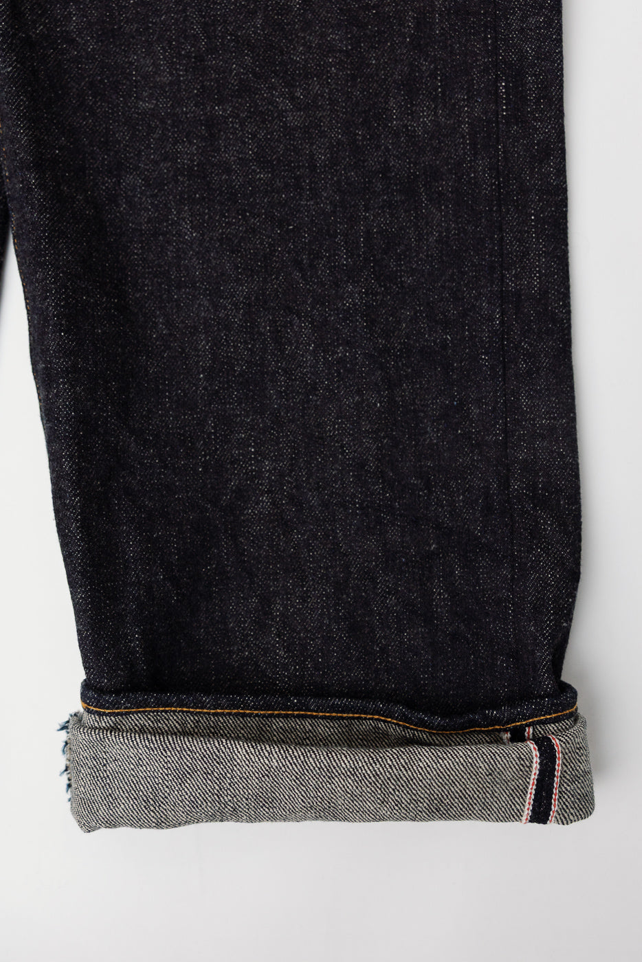 Close-up of cuff and selvedge edge on dark indigo secret denim jeans, front lower leg view.