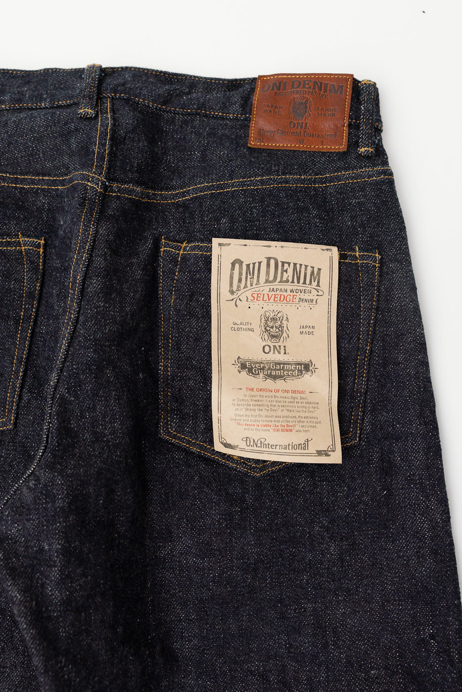 Close-up of back side of Oni Denim dark indigo selvedge jeans showing leather patch, paper tag, and rear pockets