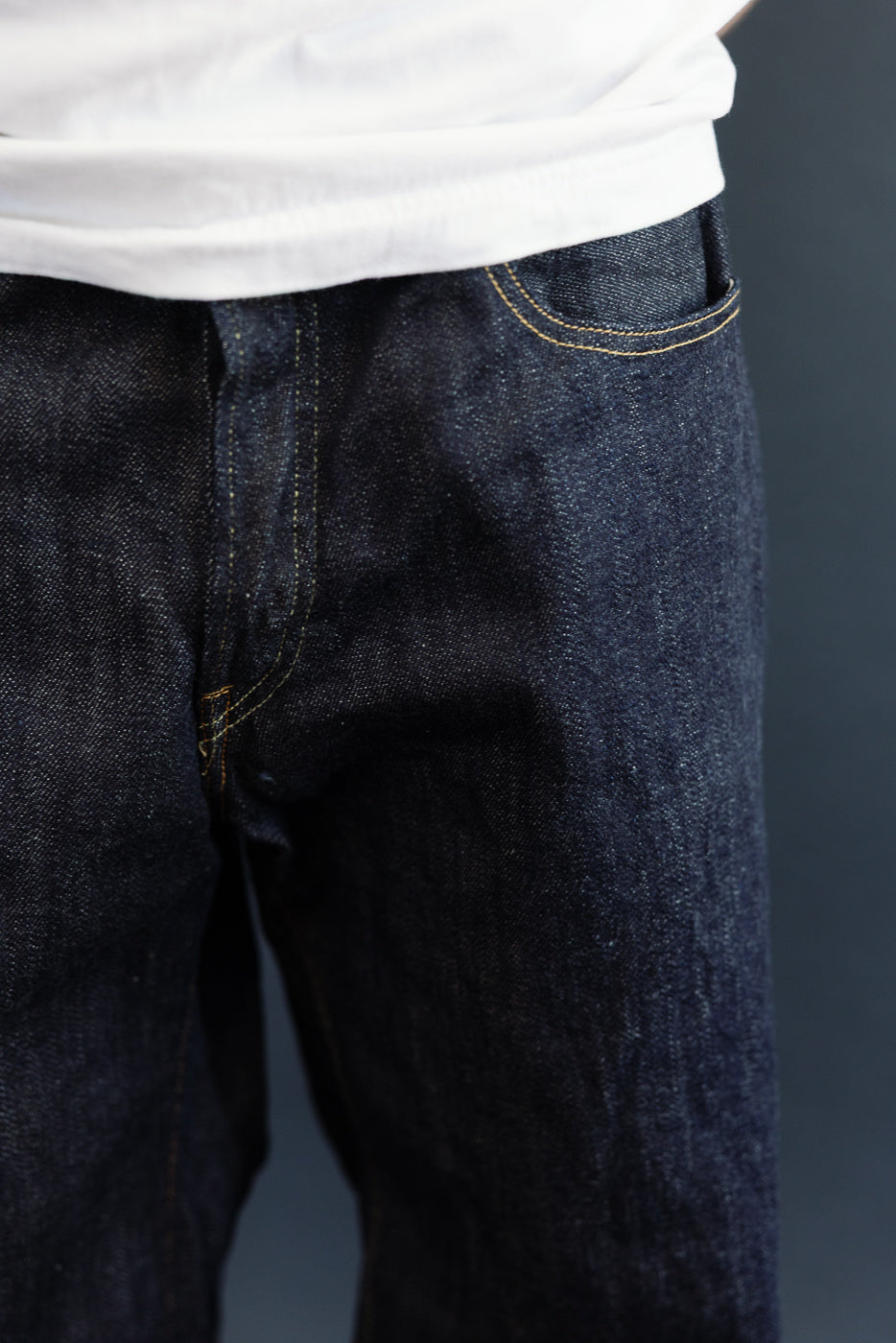Close-up front view of dark selvedge denim jeans on male model, 5'9