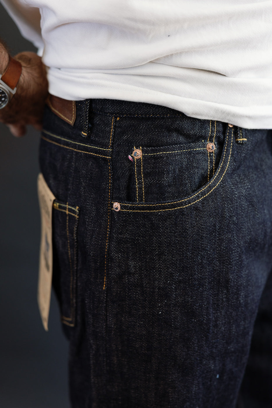 Close-up front view of dark selvedge denim jeans on male model, 5'9