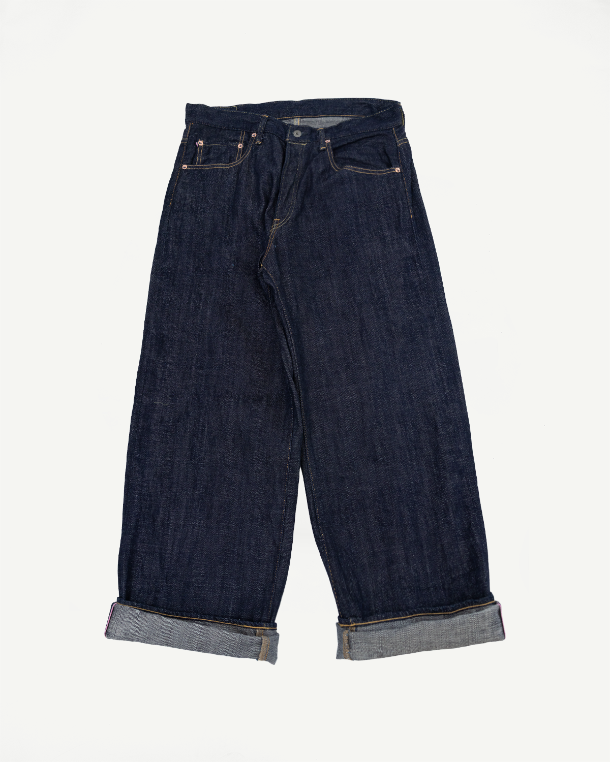 Front view of dark selvedge denim wide-leg jeans with cuffed hems, showing front pockets and button fly