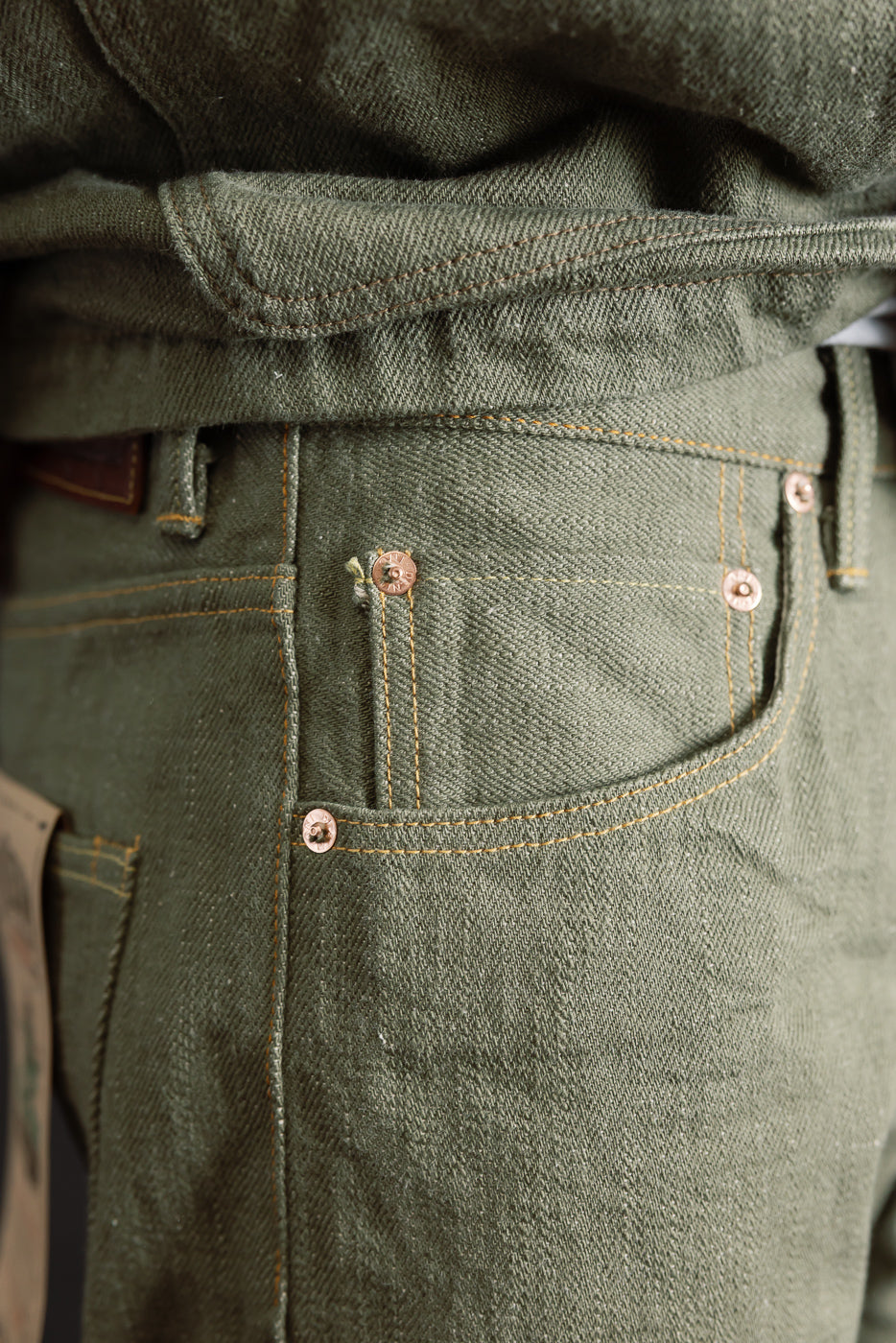 Close-up of front right pocket and coin pocket detail, olive selvedge denim jeans on male model