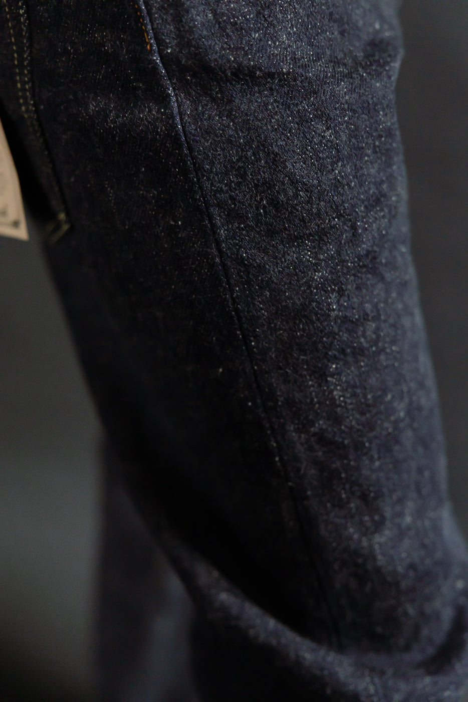 Close-up of ONI dark indigo secret denim selvedge jeans, highlighting fabric texture and seam detail.