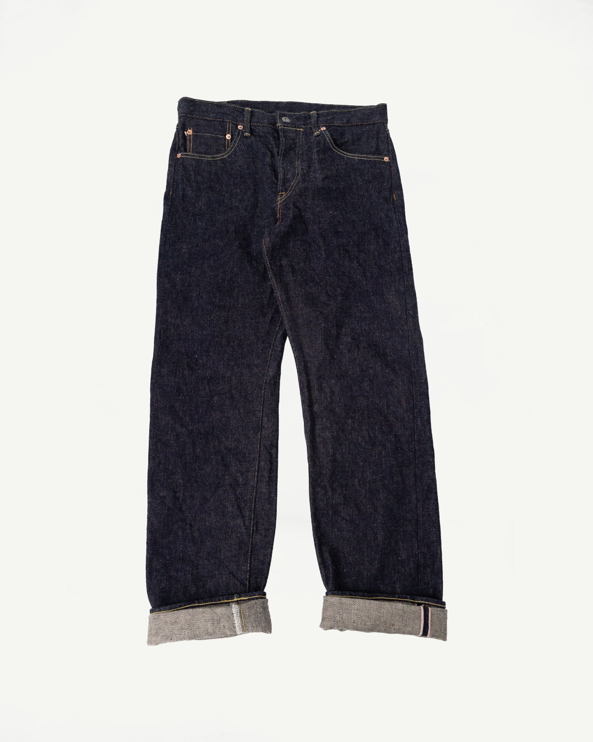 Full front flat lay of dark indigo selvedge denim jeans, straight fit, with cuffed hems