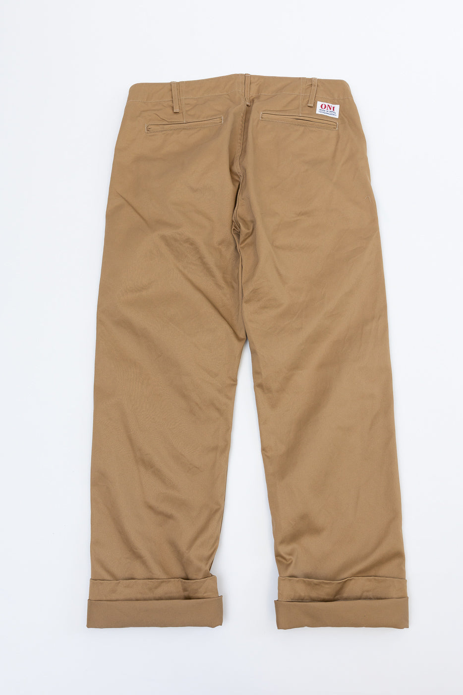 Back view of tan chinos with cuffed hems, rear pockets, and ONI brand tag on waistband