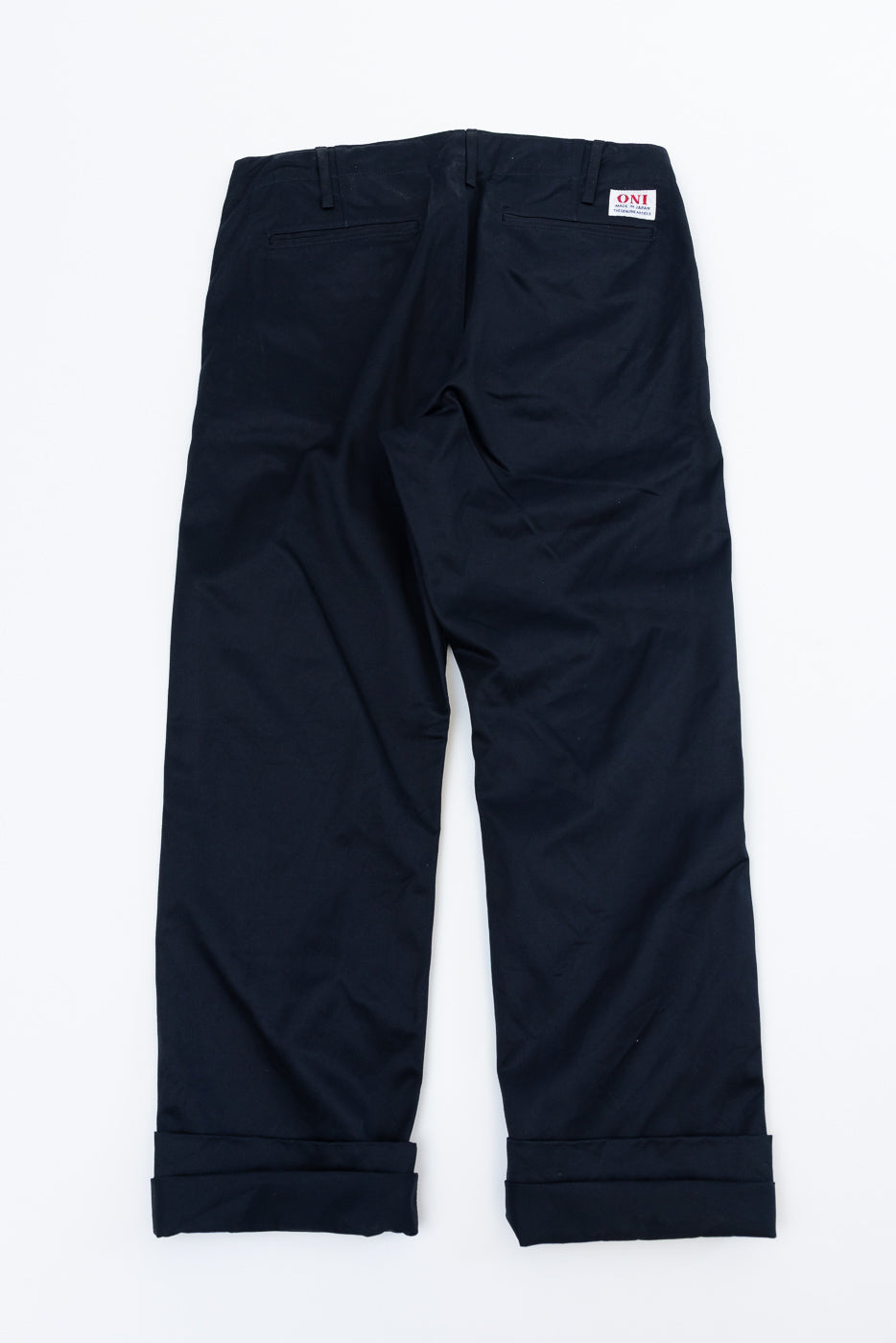 Back view of navy chinos with cuffed hems, rear pockets, and ONI brand tag on waistband