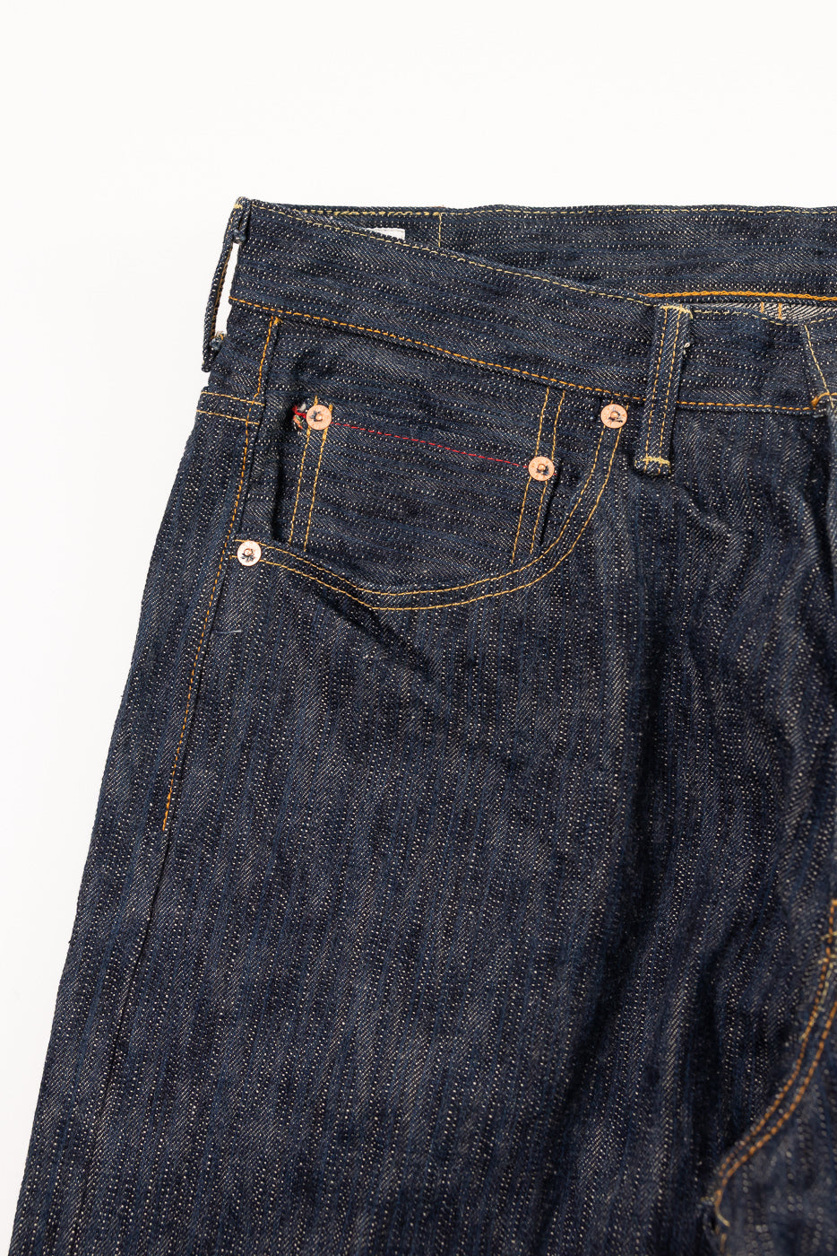 Close-up of front left upper section of ONI 16oz Kase selvedge denim jeans, highlighting pocket, stitching, and rivet details.