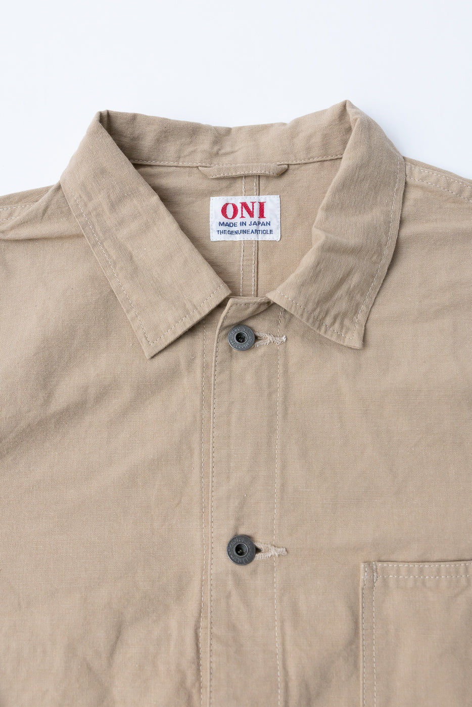 Close-up front view of beige work shirt collar, buttons, and ONI brand tag; Made in Japan detail visible