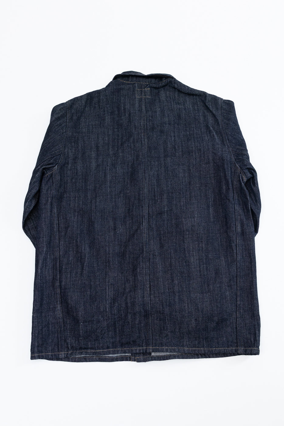 Back view flat lay of dark selvedge denim shirt jacket, showing yoke seam, sleeve construction, and hem detail