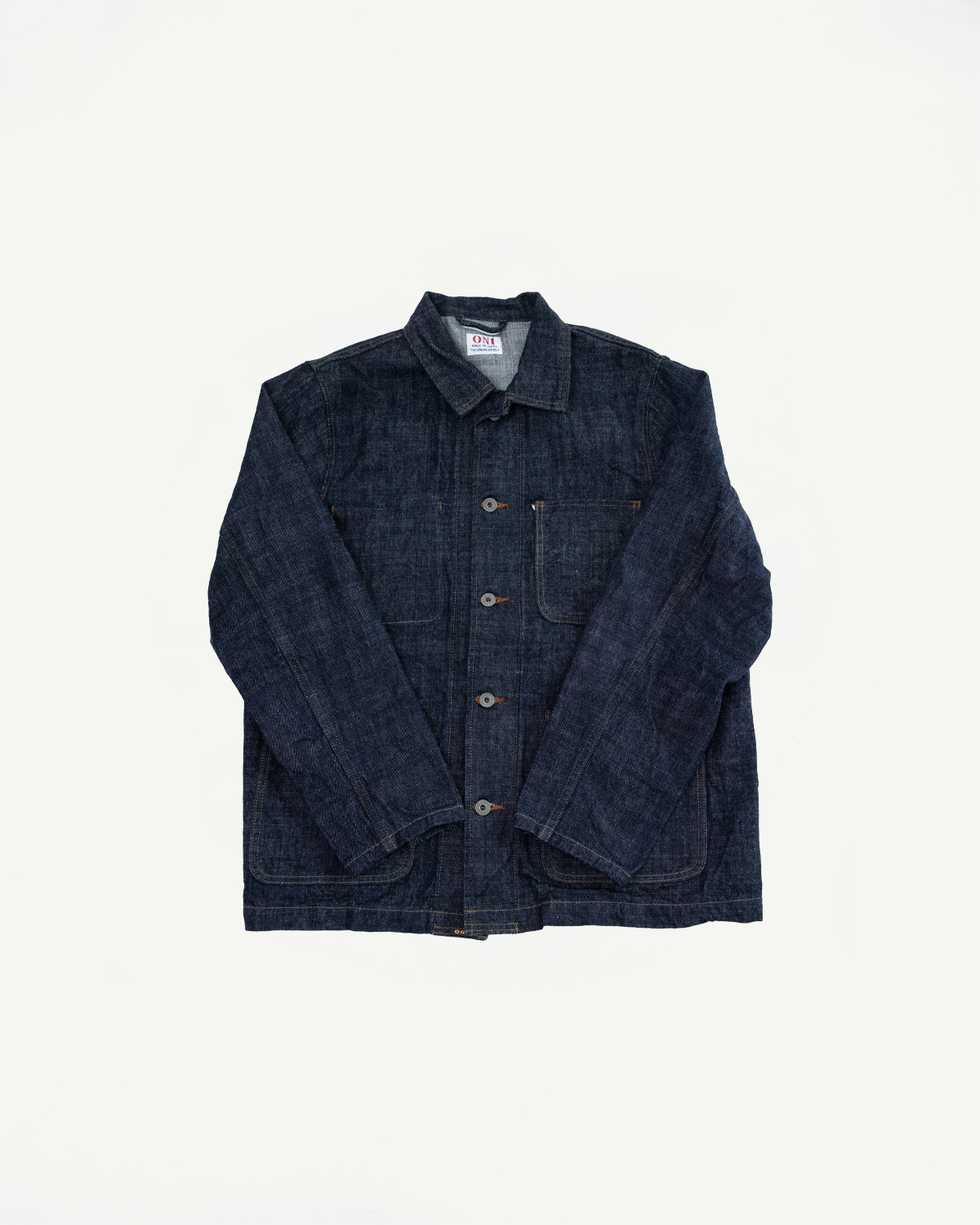Front view of dark denim chore jacket with button closure, chest pockets, and visible brand tag on collar.