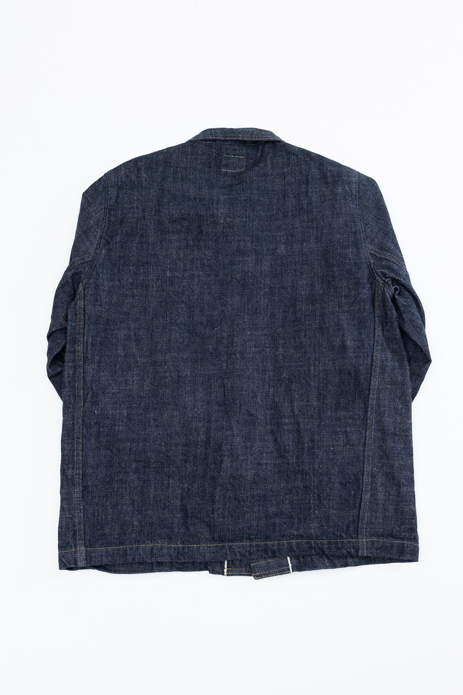Back view flat lay of dark selvedge denim jacket, showing collar, seams, and hem detail