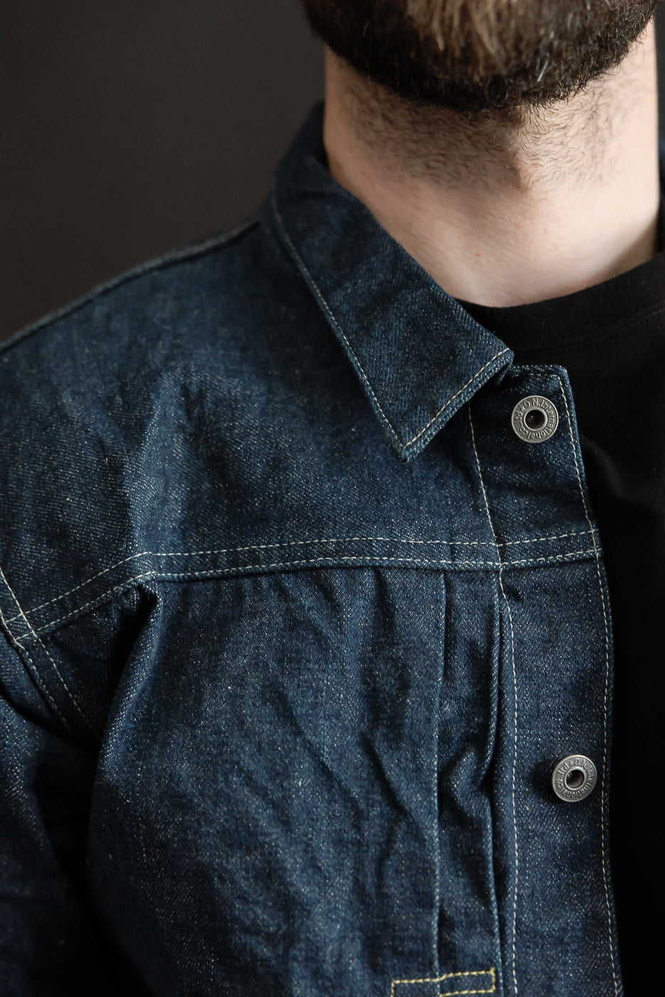 Close-up of male model wearing 15oz selvedge denim jacket front left, showing collar and metal button detail