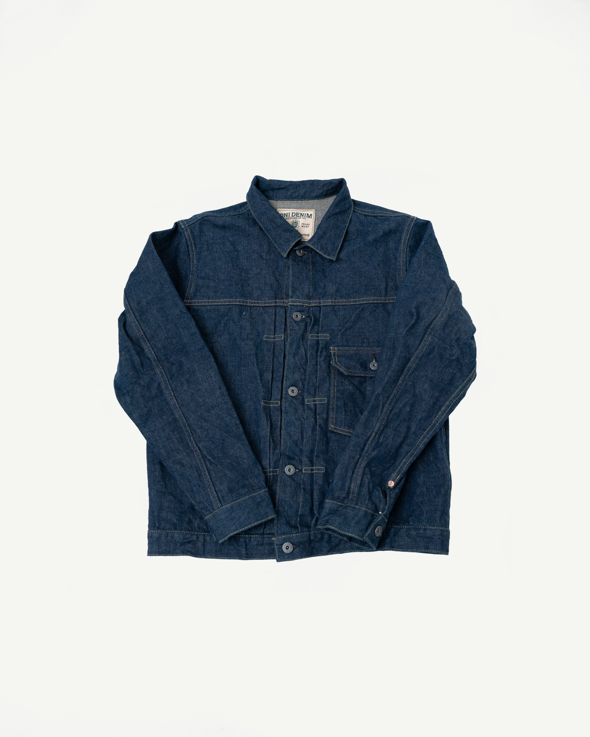 Flat lay, front view of selvedge denim jacket showing button front, chest pocket, and collar details.