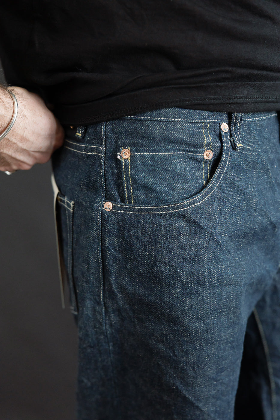 Close-up of front right pocket and side seam on selvedge denim jeans, worn by male model, 5'9