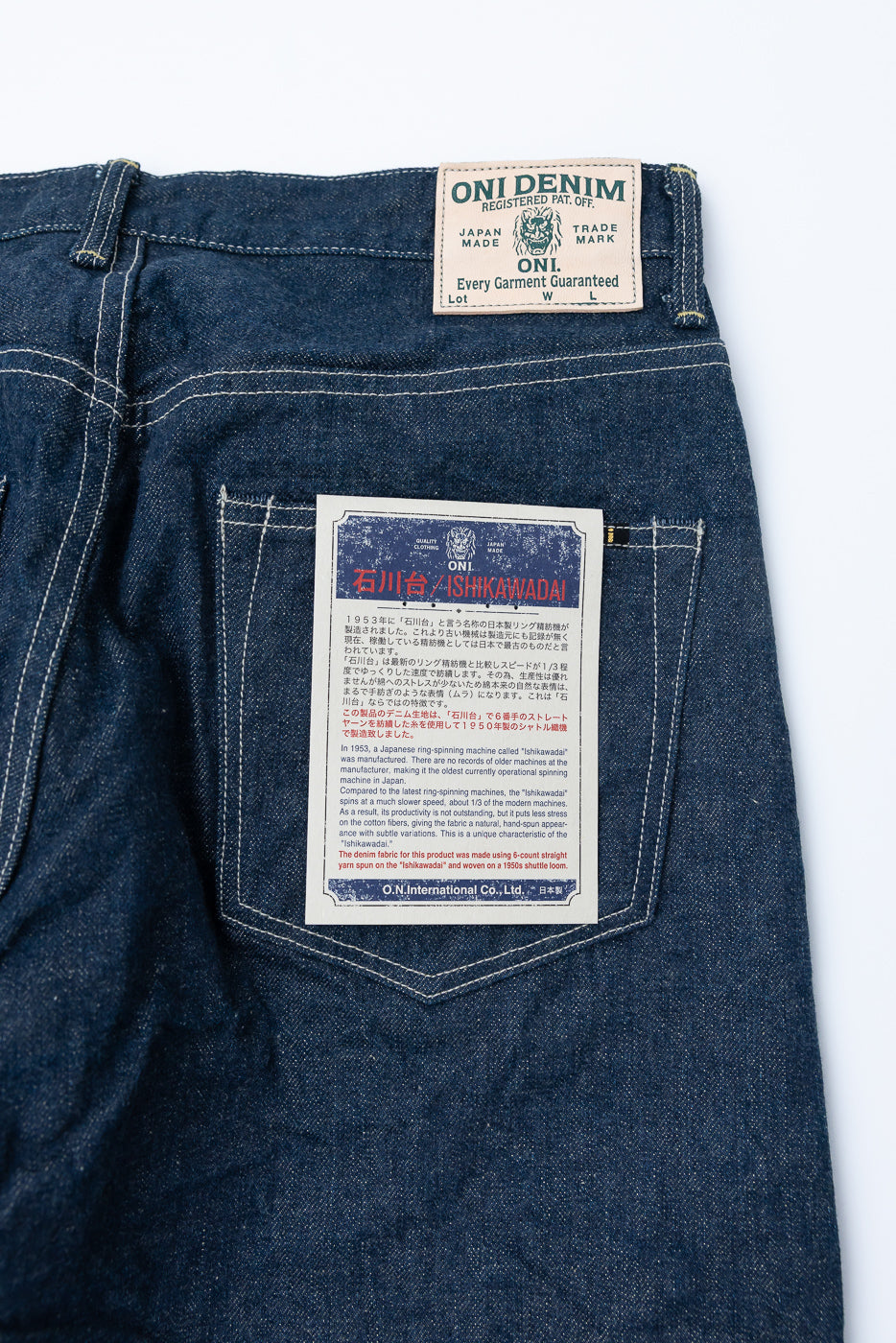 Close-up of back side of ONI Denim jeans, showing rear pocket, patch, and product label.