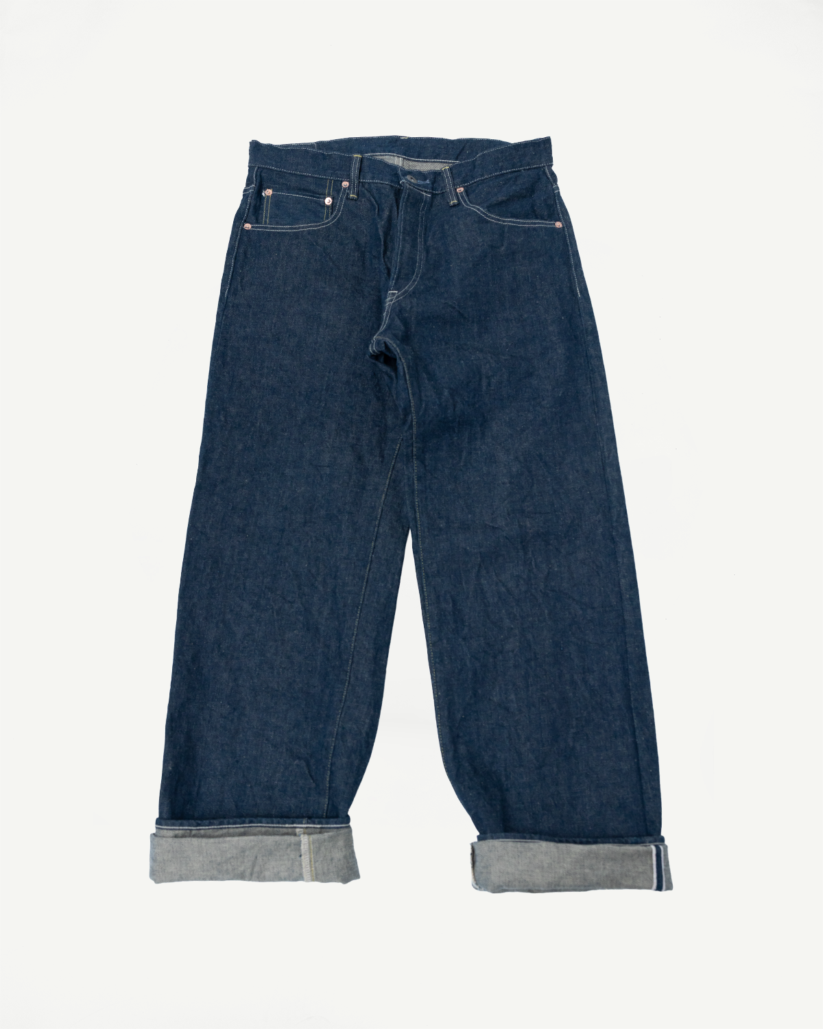 Flat lay of front view wide straight 15oz selvedge denim jeans, cuffed hem, five-pocket style.