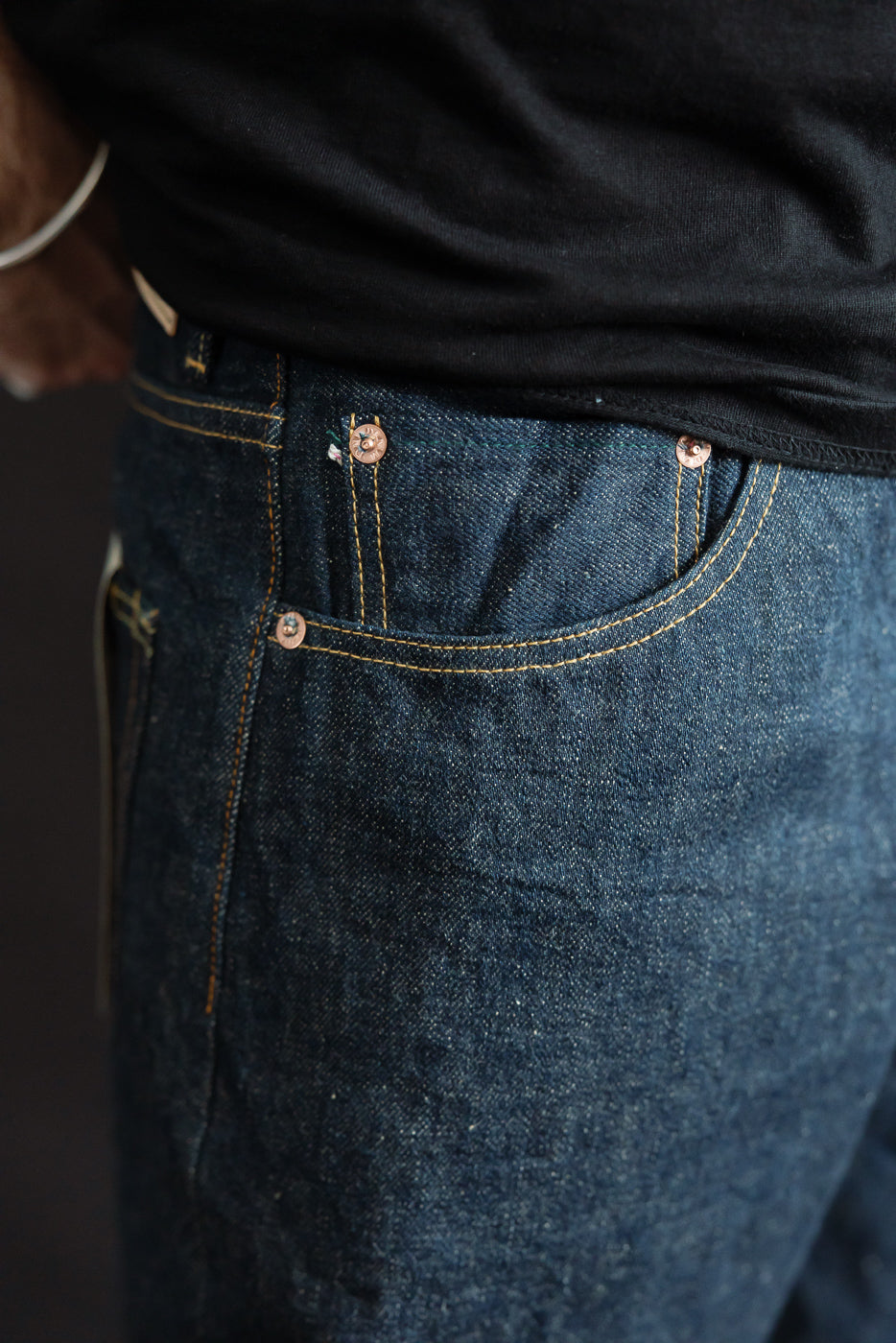 Close-up of men's selvedge denim jeans front pocket, copper rivets, male model, athletic build