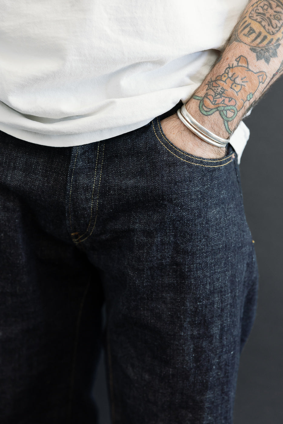 Close-up front view of dark selvedge denim jeans on male model, 5'9