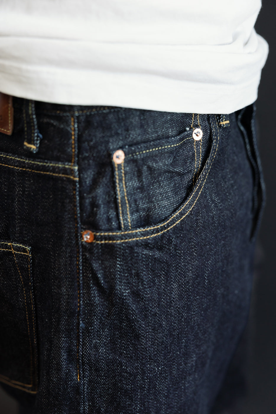 Close-up front view of dark selvedge denim jeans on male model, 5'9