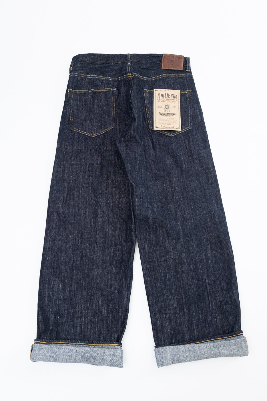 Back view of selvedge denim jeans with cuffed hems, showing back pockets and brand patch