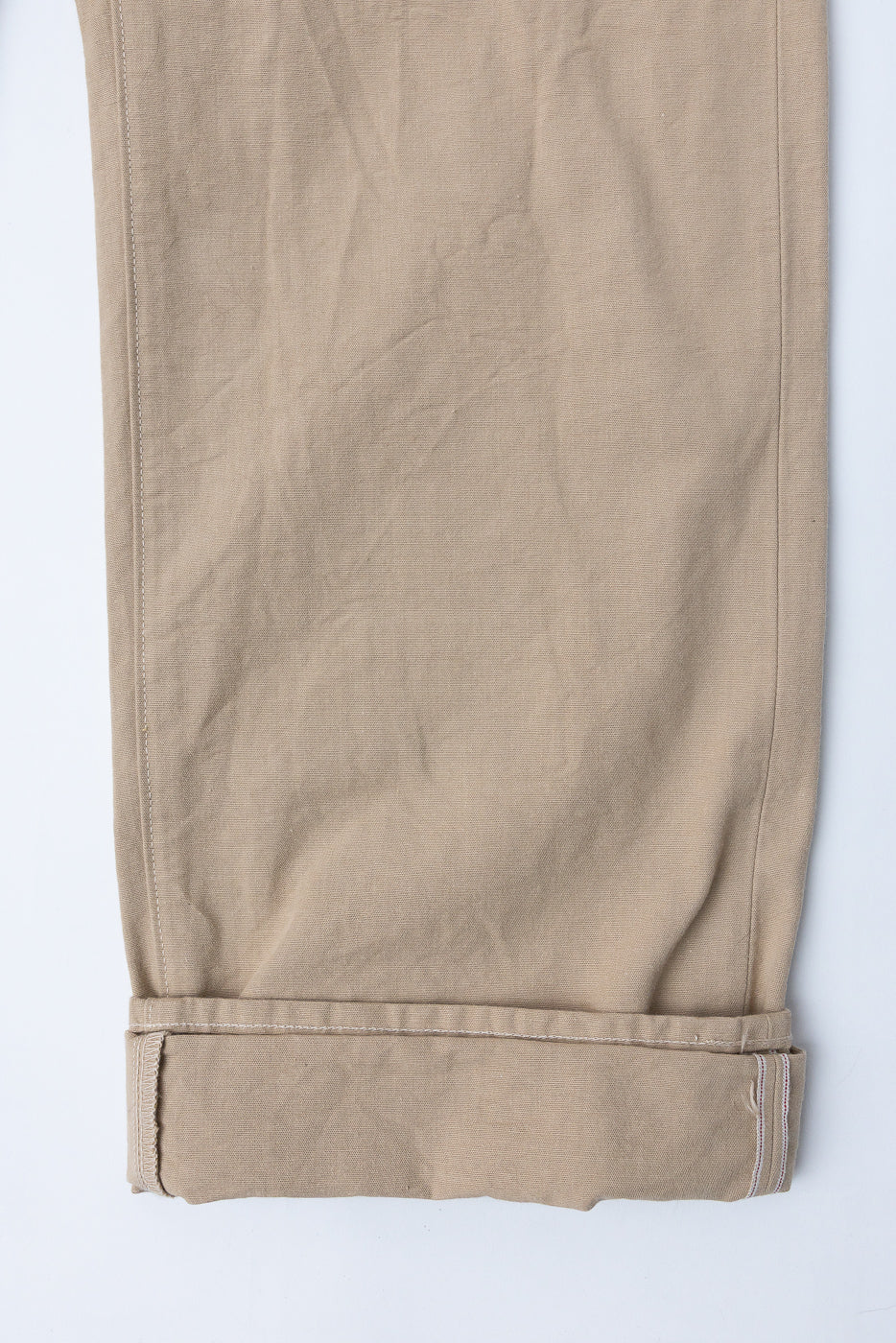 Close-up front view of beige casual pants with rolled hem and visible stitching detail