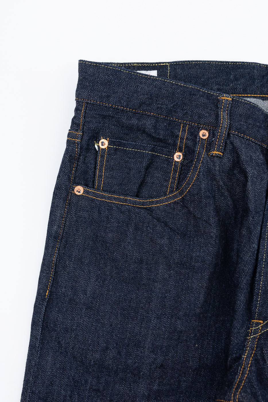 Close-up of the front right pocket and waistband of dark indigo selvedge denim jeans.