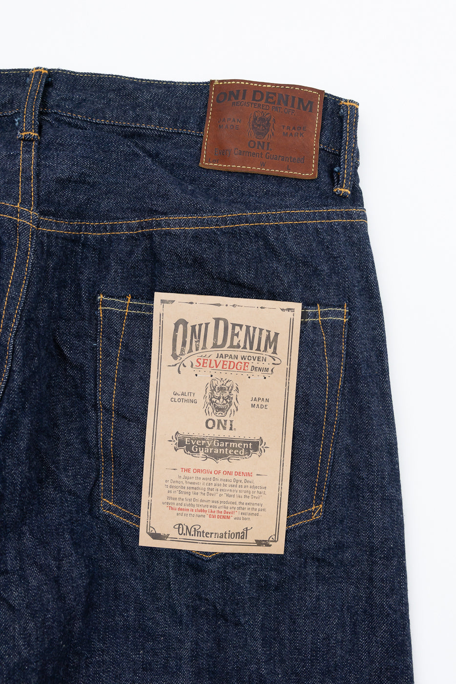 Close-up of the front waistband and back pocket of Oni Denim selvedge jeans, showing leather and paper tags.