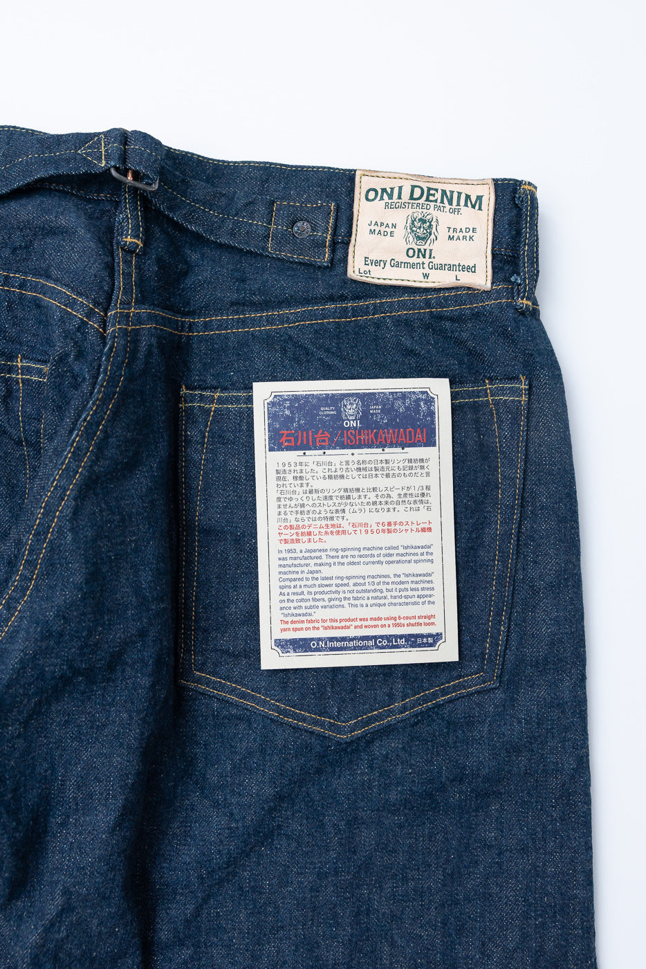 Close-up of the back side of ONI Denim jeans, showing cinch back, leather patch, and back pocket tag.